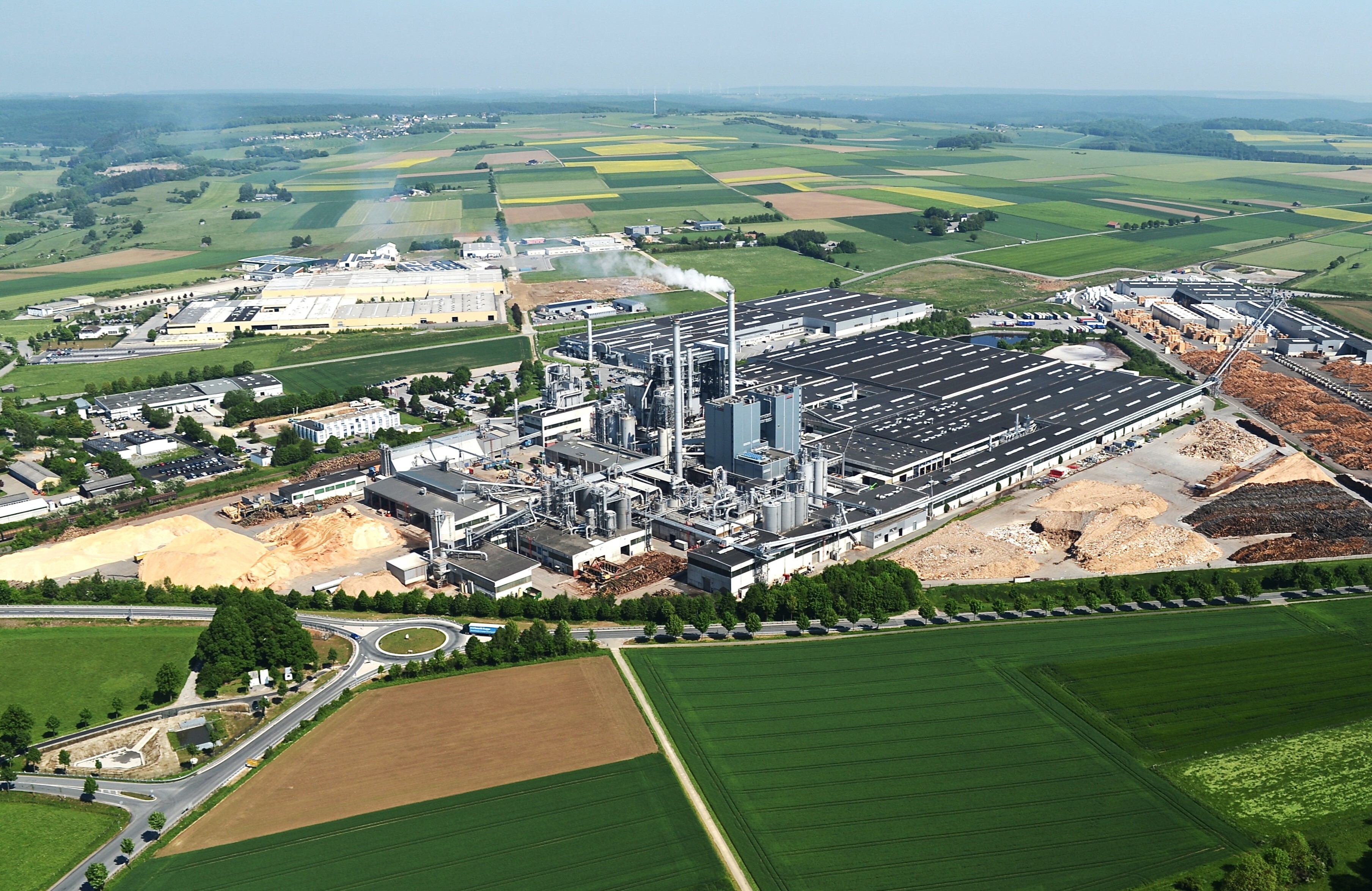 Luftaufnahme der Egger-Gesamtanlage in Brilon mit Produktionshallen, Holzlagerflächen und umgebenden Feldern.