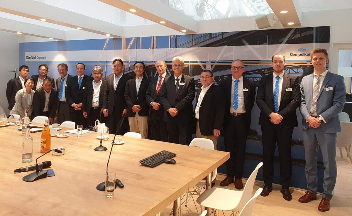 Gruppenfoto von SIEMPELKAMP-Mitarbeitenden und internationalen Geschäftspartnern bei einem Meeting.