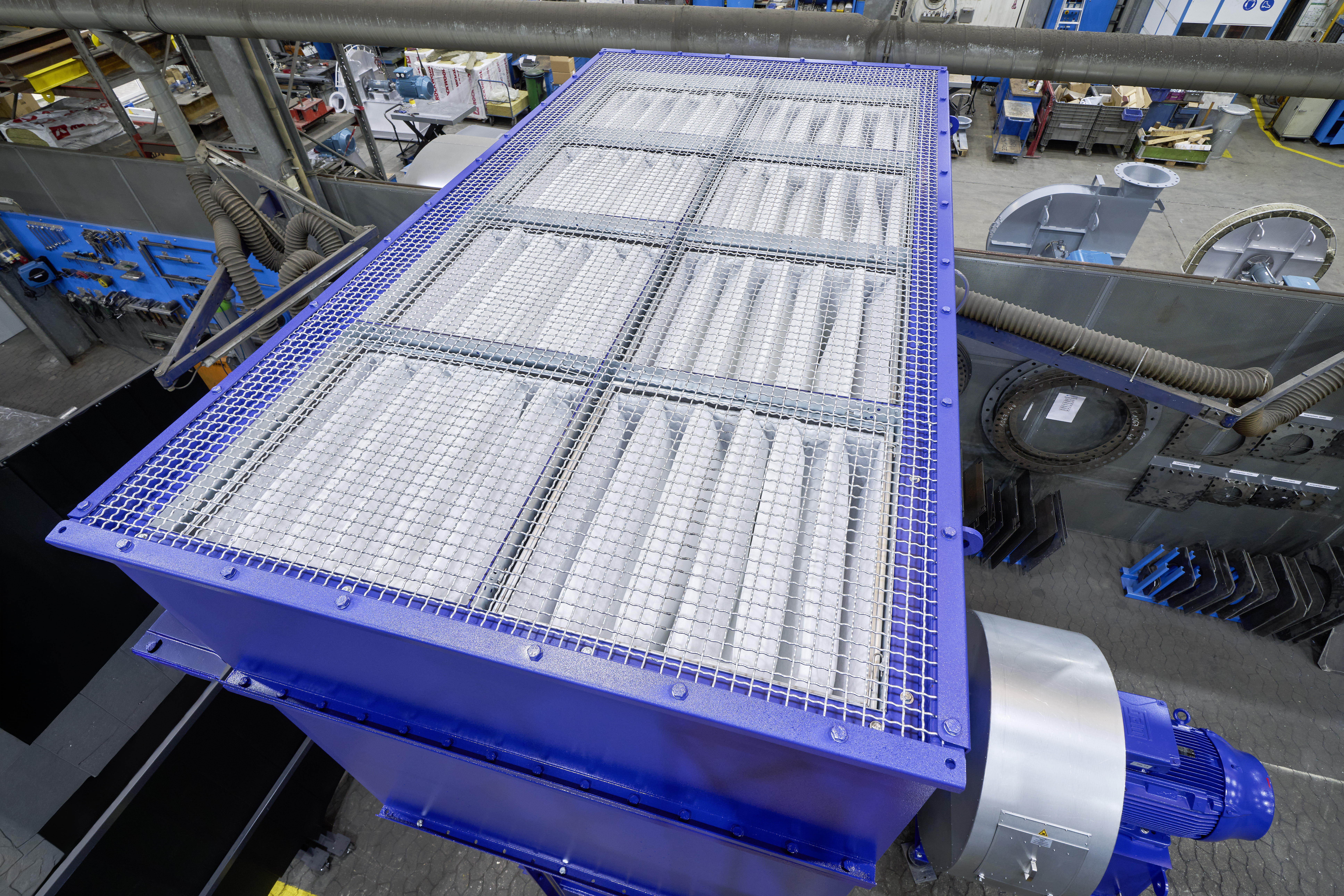 Blaue Filtereinheit von Siempelkamp Industrial Fans mit begehbarem Schutzgitter in einer Fertigungshalle.
