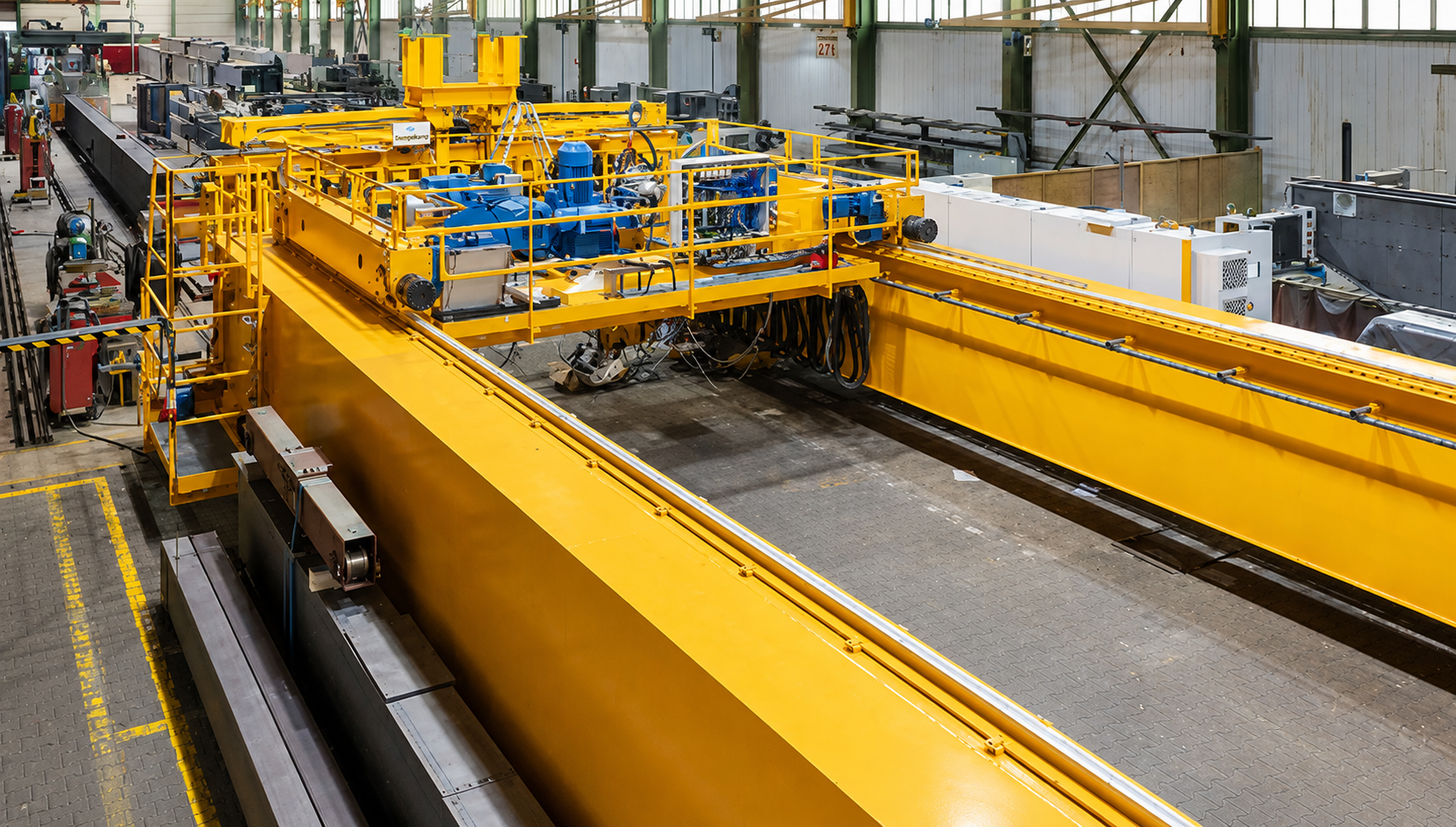 Gelber Siempelkamp Brückenkran in einer industriellen Fertigungshalle.